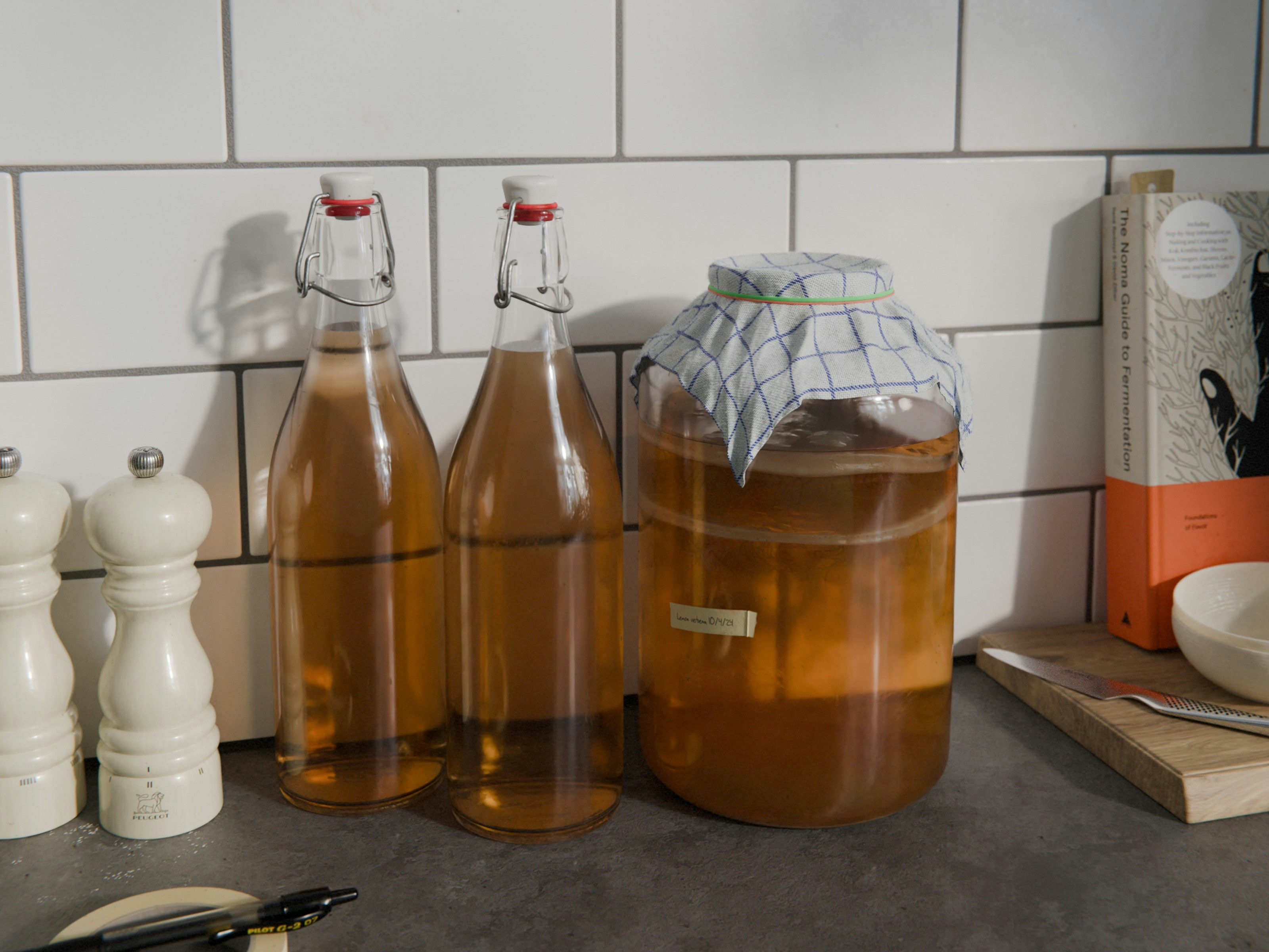 Render of two bottles of Kombucha and a mason jar with kombucha scoby culture brewing.